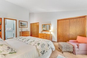 A bedroom with a bed, a dresser, a pink chair, and a wardrobe. - Loonsight - PET FRIENDLY (Minocqua)