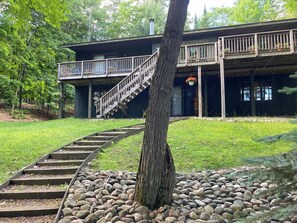 A wooden staircase leading to a deck with a railing, surrounded by a grassy area and a tree. - Loonsight - PET FRIENDLY (Minocqua)