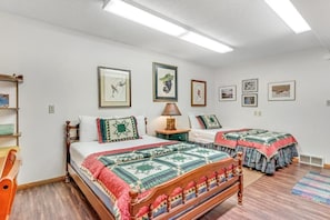 A bedroom with two beds, a wooden chair, a nightstand, and framed pictures on the wall. - Loonsight - PET FRIENDLY (Minocqua)