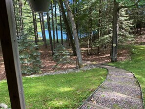 A wooden boardwalk curving through a forested area with a lake in the background. - Loonsight - PET FRIENDLY (Minocqua)
