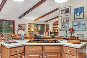 A cozy living room with a wooden dining table, comfortable seating, and a bookshelf filled with books. - Loonsight - PET FRIENDLY (Minocqua)