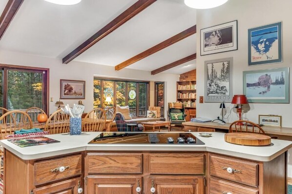 A cozy living room with a wooden dining table, comfortable seating, and a bookshelf filled with books.