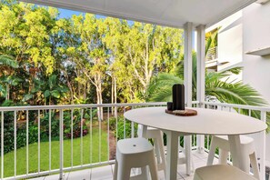 Enjoy a serene view of the lush garden from this balcony, featuring a round table and two chairs.