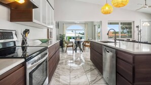 A modern kitchen with a large island, dark wood cabinets, and a view to the outside.