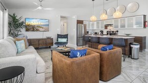 A modern living room with a sofa, ottoman, and a dining area with chairs.