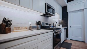 A modern kitchen with white cabinets, a microwave, a toaster, and a stove. - Patio 2BR St Louis Rental – Gateway Arch Access (St. Louis)