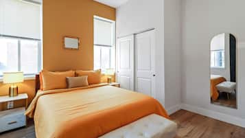 A bedroom with a large bed, bedside tables, a mirror, and a view of the outside.