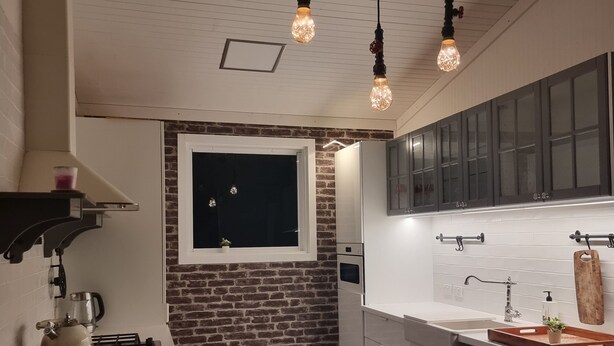 A modern kitchen with a brick accent wall, a window, and pendant lighting. - Private cabin on 5 acres with WiFi, AC & pet friendly  (Curra)
