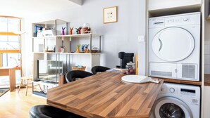 Un espacio habitable funcional con una mesa de comedor de madera, lavadora y televisor.