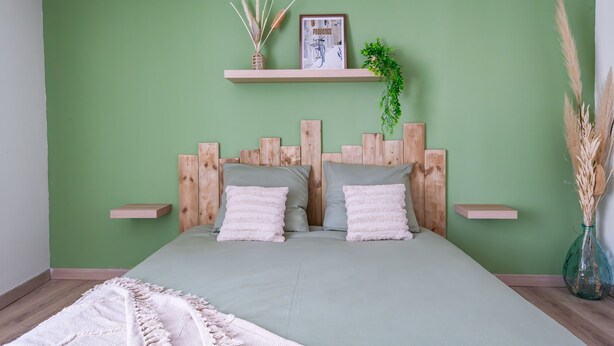 A bedroom with a green wall, wooden headboard, two bedside tables, a bed with grey bedding, a hanging plant, and a framed picture. - Douce vie en Provence  (Malaucène)