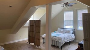 A bedroom with a sloped ceiling, a bed, a ceiling fan, and a window. - Country farm cottage (Nesmith)
