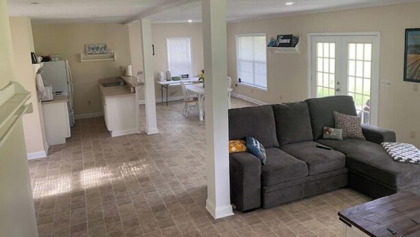 A spacious living area with a grey sofa, a dining table, and a kitchen in the background. - Country farm cottage (Nesmith)