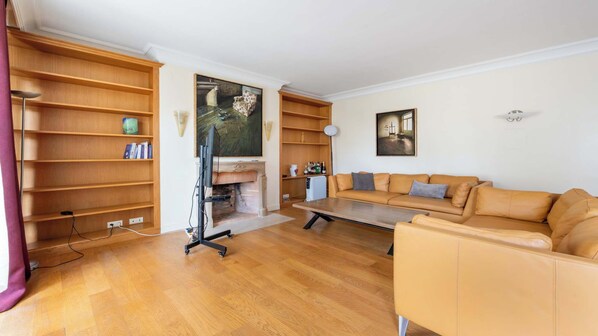Una sala de estar con sofá, estanterías de madera, chimenea y televisor.