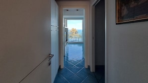 Un couloir donnant sur un balcon, dont le sol est carrelé, et une porte menant à une pièce.