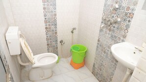 A small bathroom with a toilet, a green bucket, a shower, and a sink. - Maharani Maya Guest House Bodhgaya  (Gaya)