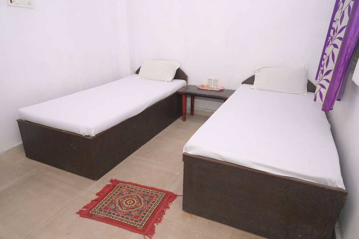 A small room with two single beds, a small table with a tray of items, and a patterned rug on the floor.