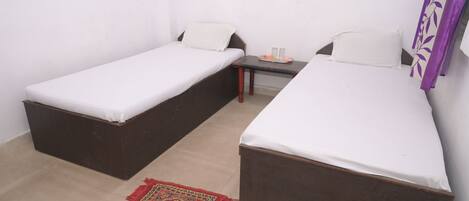 A small room with two single beds, a small table with a tray of items, and a patterned rug on the floor.