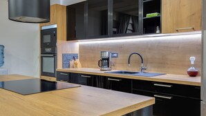 Una cocina moderna con encimera de madera, armarios negros, cafetera y fregadero.