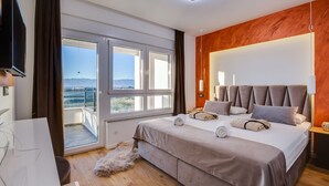 Una habitación de hotel moderna con una cama grande, un balcón con vistas, un televisor de pantalla plana y una pared decorativa de madera.