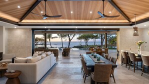 Un espacio habitable moderno y abierto con un gran ventanal con vistas panorámicas, una zona de comedor con muebles de madera y un ventilador de techo.