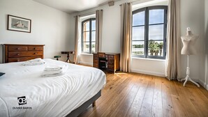 Ein Schlafzimmer mit einem großen Bett, einem hölzernen Schminktisch, einem Schreibtisch und einer Mannequin.