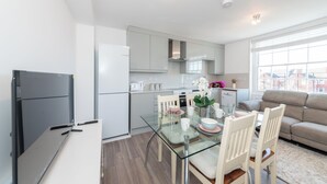 A modern kitchen with a dining area, including a glass table, chairs, and a sofa. - Entire Reading Flat RG1 (Reading)