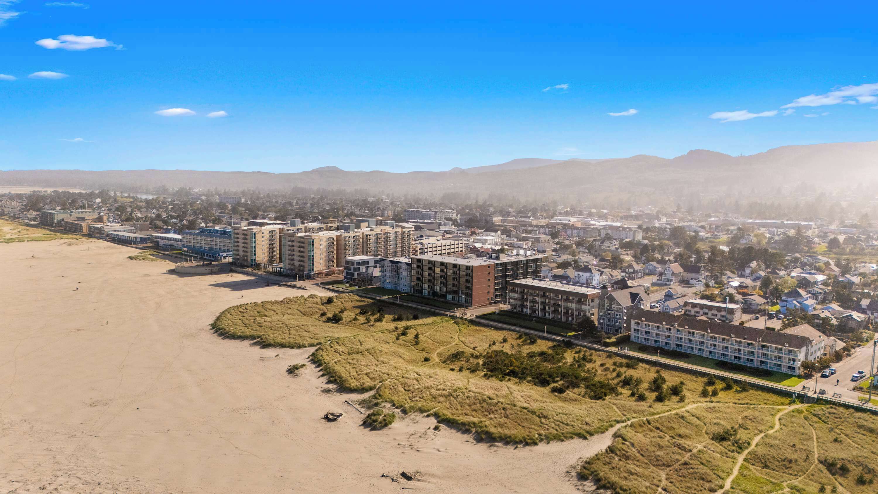 Eine Küstenstadt mit Hochhäusern, einem Strand und einer hügeligen Landschaft im Hintergrund.
