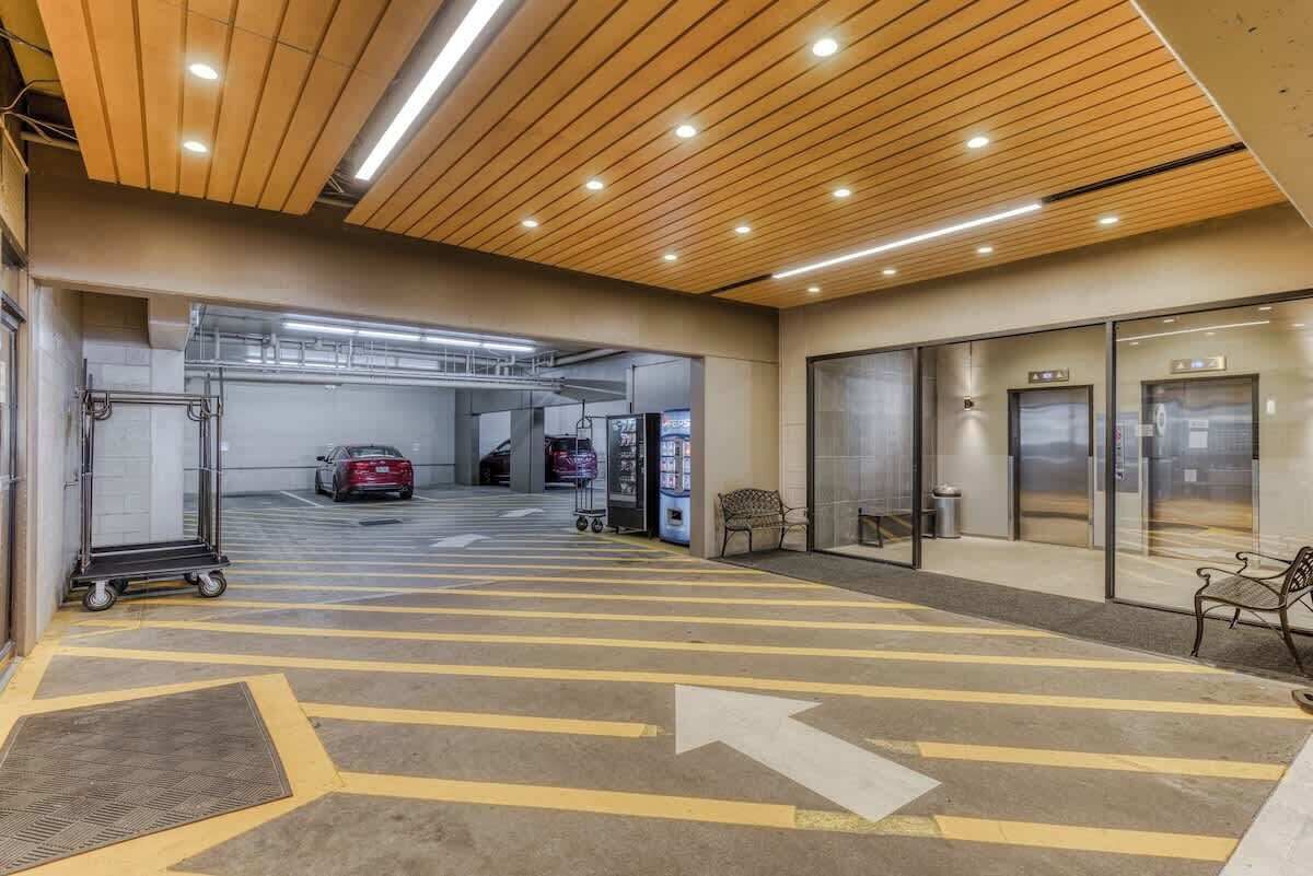 A clean, modern indoor parking area with directional arrows on the floor, a vending machine, and a car in the background.