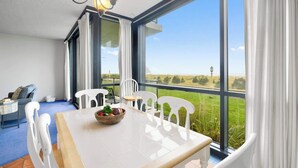Une chambre moderne dotée d’une grande fenêtre, d’une table à manger avec des chaises et offrant une vue sur la campagne.