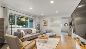 Una sala moderna con un sofá gris, una mesa de centro de madera y un ventanal grande.