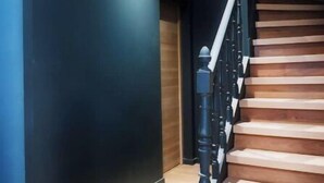 A staircase with wooden steps and black balusters, leading to a landing with a dark wall and a light-colored floor. - 4-Charming stay in a renovated farmhouse (Saint-Quentin)