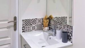 A bathroom with a white sink, a mirror, and patterned tiles. - 4-Charming stay in a renovated farmhouse (Saint-Quentin)