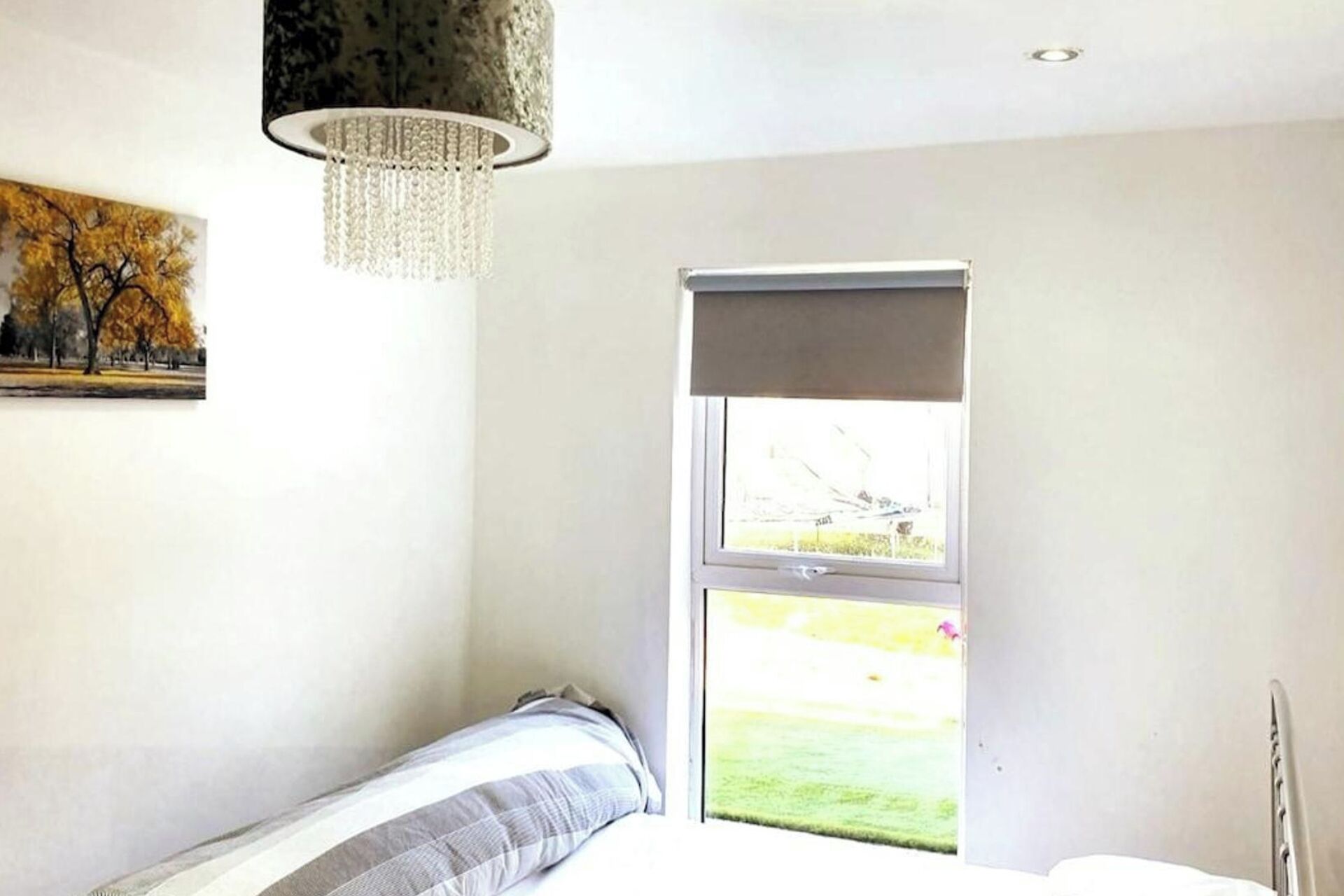 A bedroom with a bed, a window, and a chandelier.