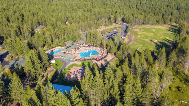 An aerial view of a resort with a swimming pool, guest cabins, and a forested area. - Tahoe Donner 4 bd Family Cabin (Truckee)
