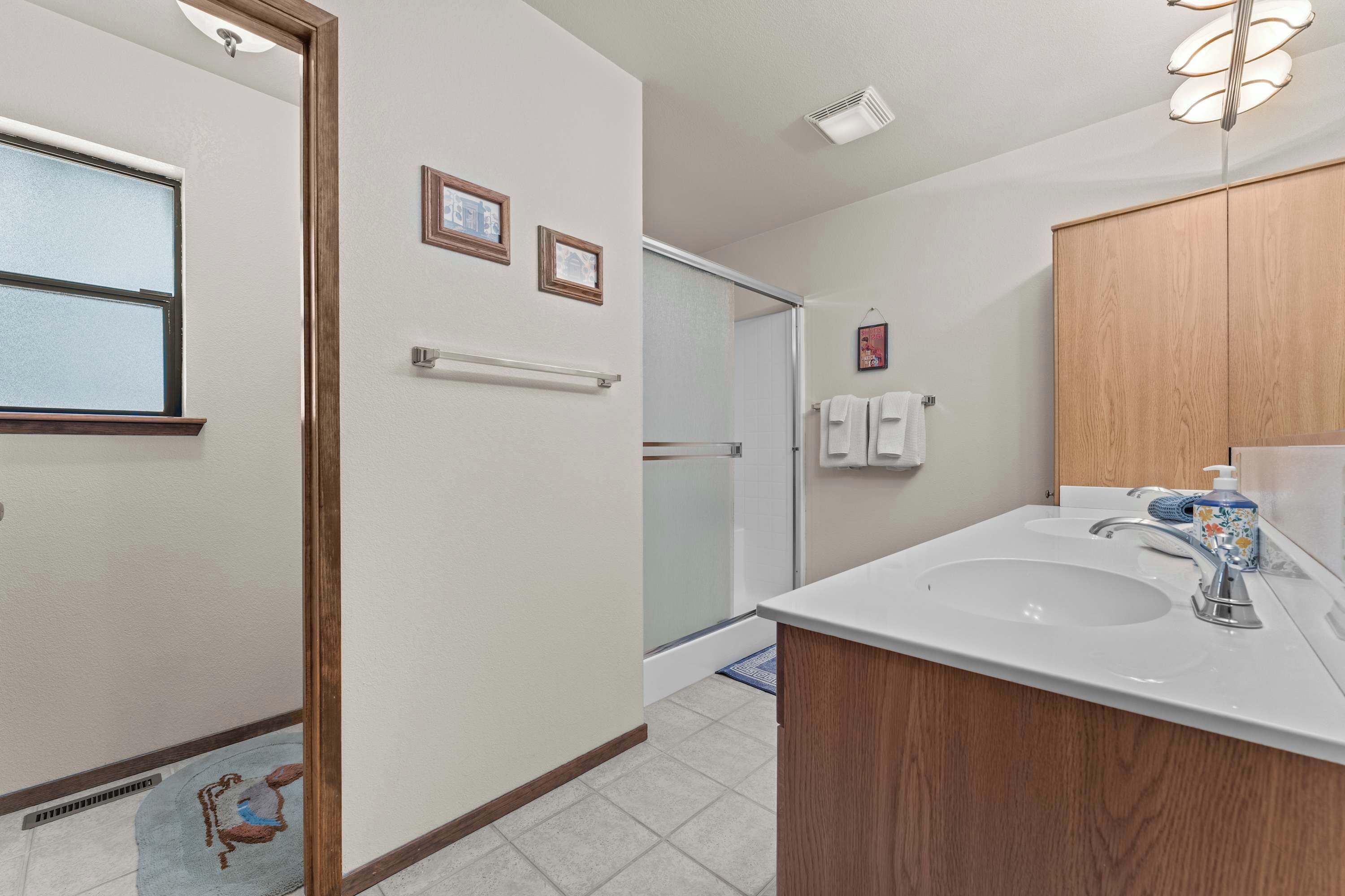 Un baño con lavamanos, espejo, toallero y zona de ducha.