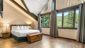 A bedroom with a large bed, wooden nightstands, a wooden chest, and a window with curtains.