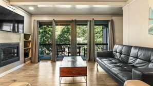 A modern living room with a black leather sofa, a wooden coffee table, and a fireplace.