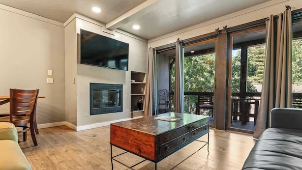 A modern living room with a wooden coffee table, a sofa, and a dining area with chairs.