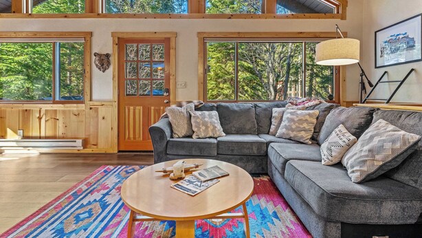 A cozy living room with a gray sectional sofa, a round coffee table, and a colorful rug. - Donner Lake Retreat Walk To Beach (Truckee)