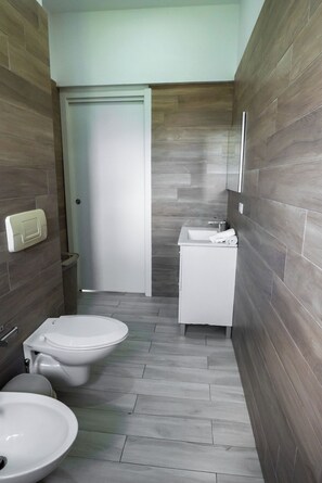 A compact bathroom with a toilet, bidet, and sink. - Baya Azul Bayahibe - Apto 306 (San Rafael del Yuma)