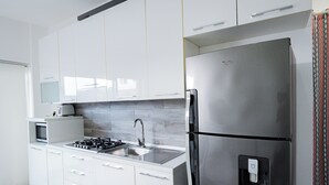 Eine moderne Küche mit weißen Schränken, einem Edelstahlkühlschrank, einer Mikrowelle und einem Spülbecken.