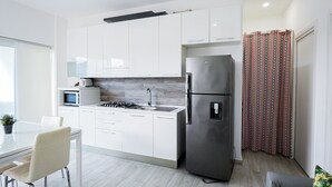 Eine moderne Küche mit weißen Schränken, einem Edelstahl-Kühlschrank, einer Mikrowelle und einem Gasherd.