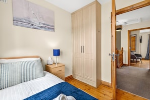 Une chambre à coucher comprenant un lit, une table de chevet, une lampe, une armoire et un miroir qui reflète une pièce avec une chaise et une porte.