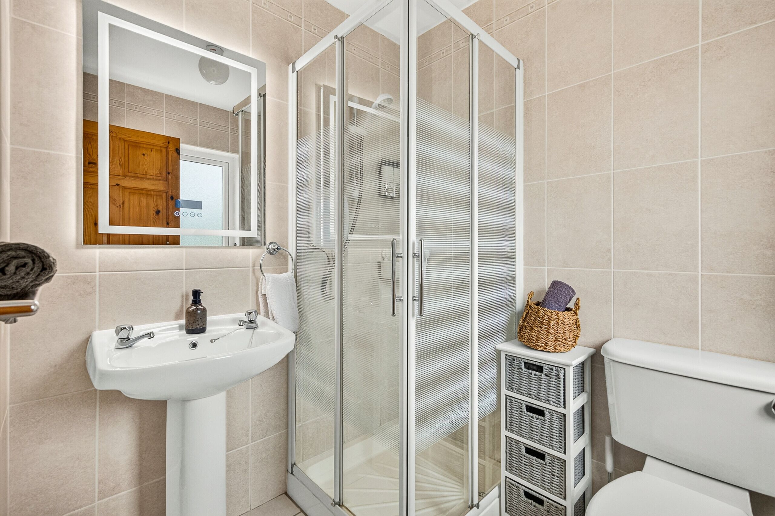 A bathroom with a glass shower enclosure, a sink, and a toilet.