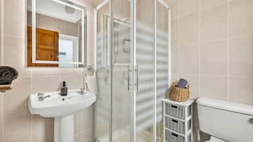 A bathroom with a glass shower enclosure, a sink, and a toilet.