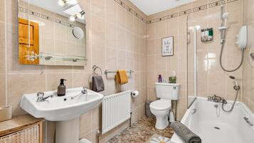 A bathroom with a bathtub, a toilet, a sink, and a mirror.