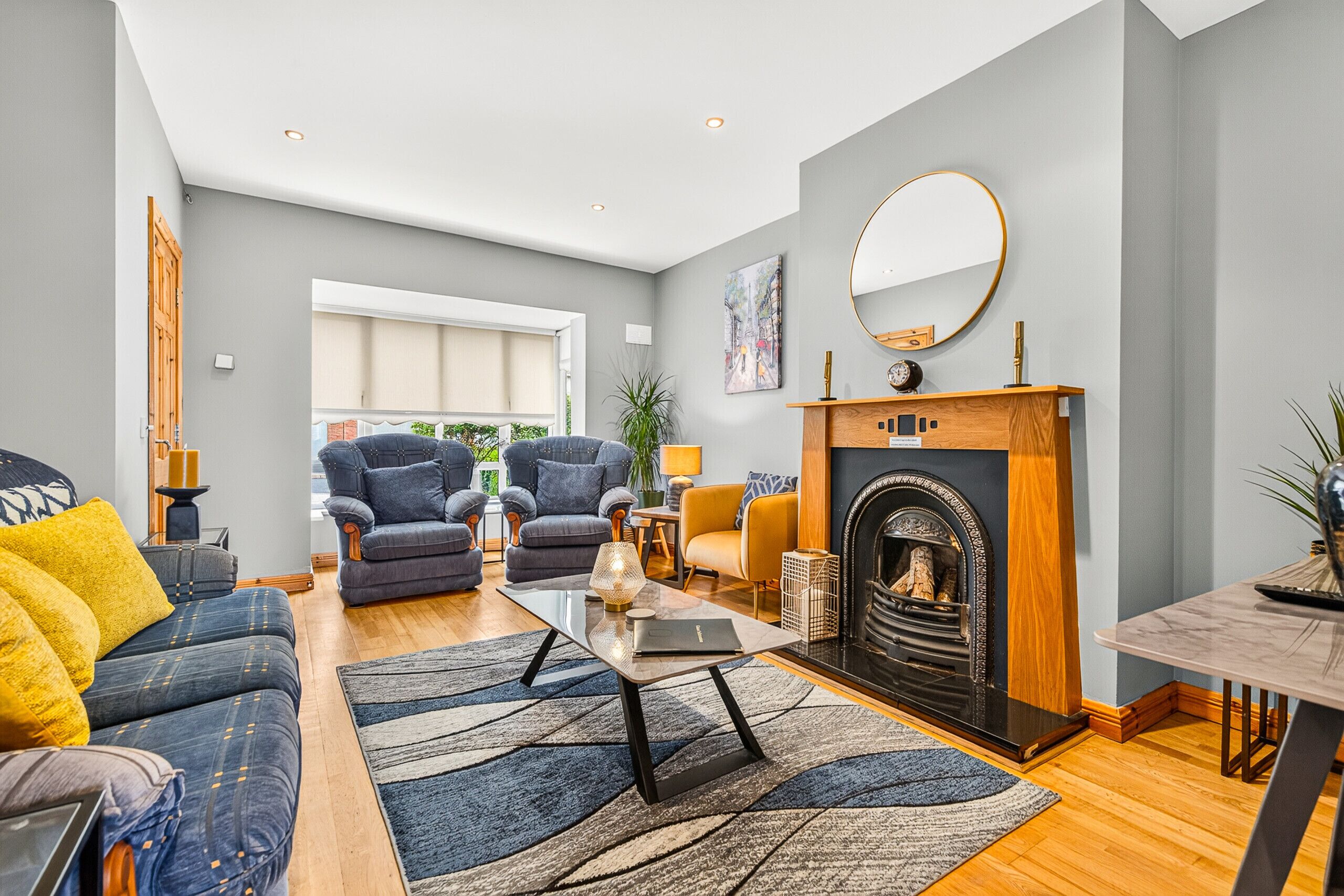 A spacious living room with a fireplace, two armchairs, a sofa, and a coffee table.