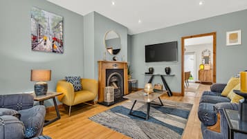 A modern living room with a fireplace, sofas, a TV, and artwork on the walls.