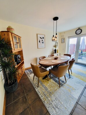 A dining area with a round table, chairs, a wooden cabinet, and a potted plant.