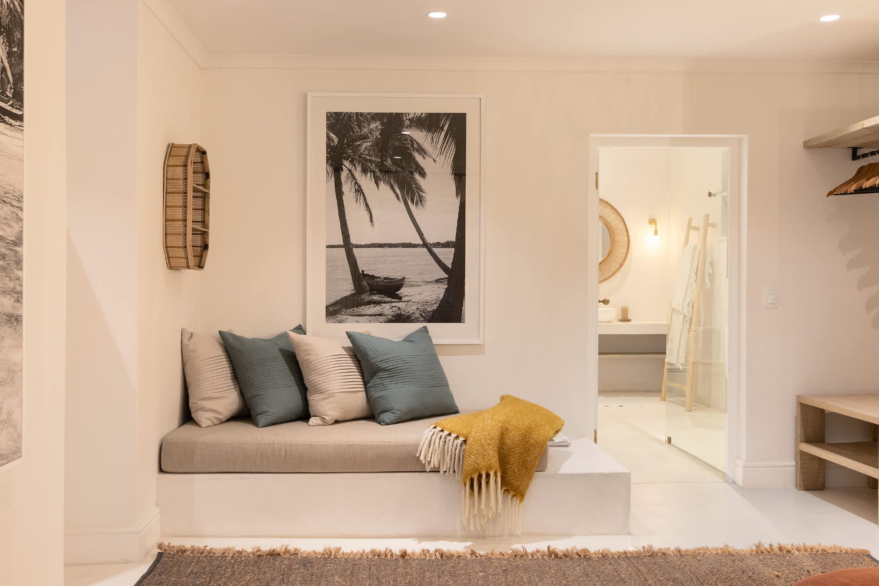 Un salon moderne avec un canapé, des coussins, un plaid et un tableau représentant une scène de plage.